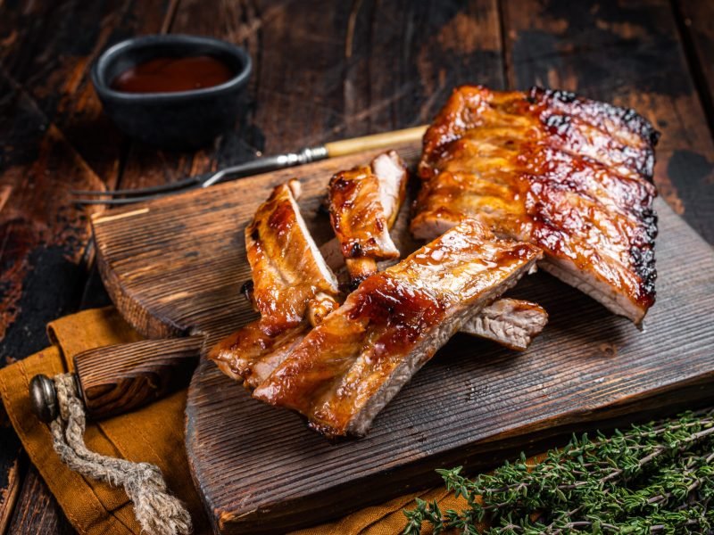 Grilled pork Baby Back spare ribs on a wooden board. Wooden background. Top view.